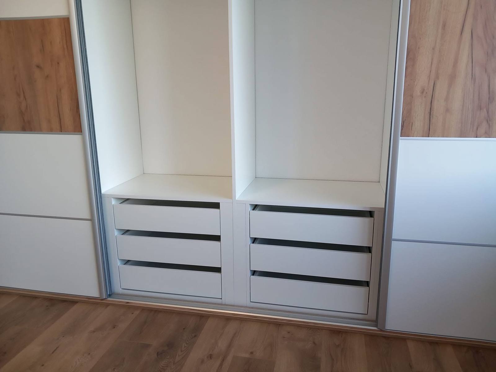 Weiße Laden mit dunklen Griffleisten unter dem Hängebereich