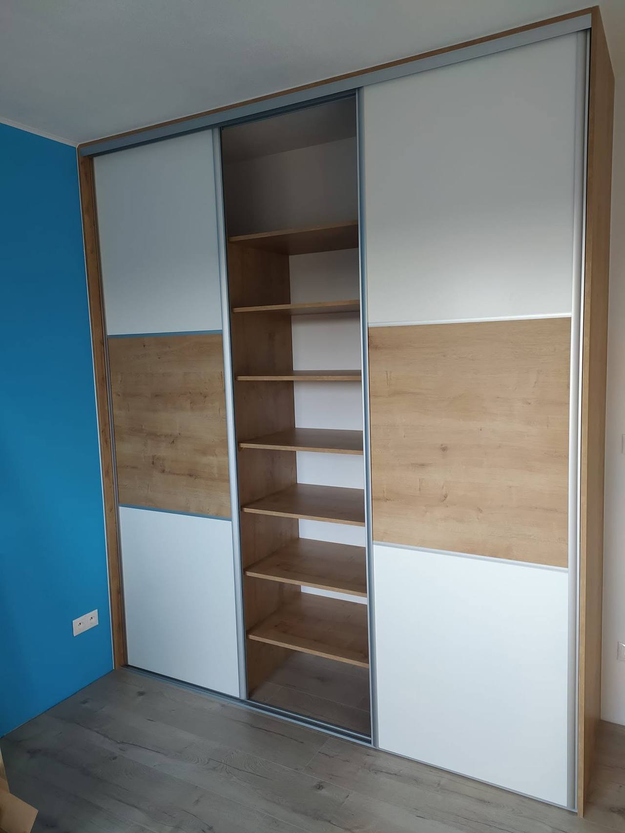Offener Mittelteil mit Fachböden in Eiche neben blauer Wand