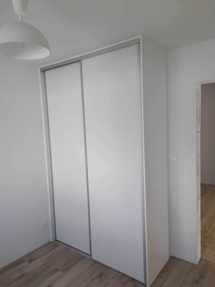 Biela posuvná skriňa zasadená do niky v izbe