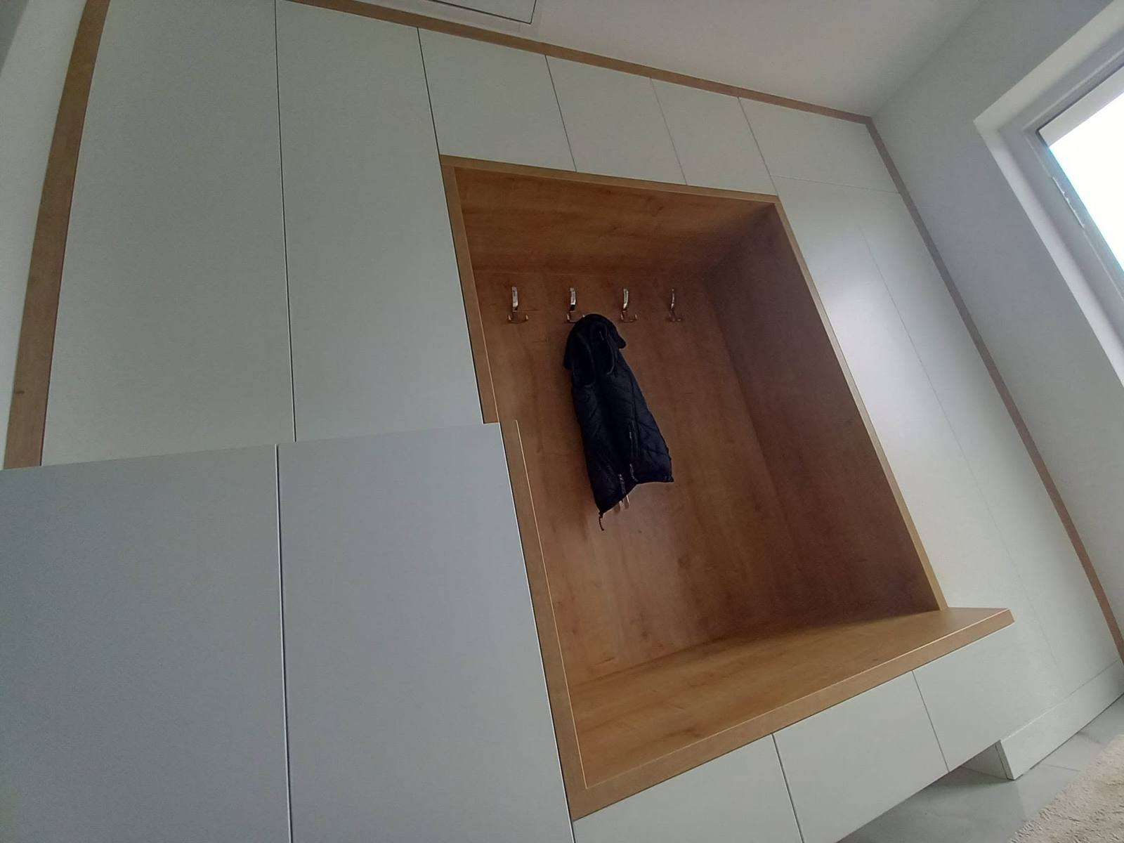 Široký pohľad na bielu stenu s dubovým rámom a nikou