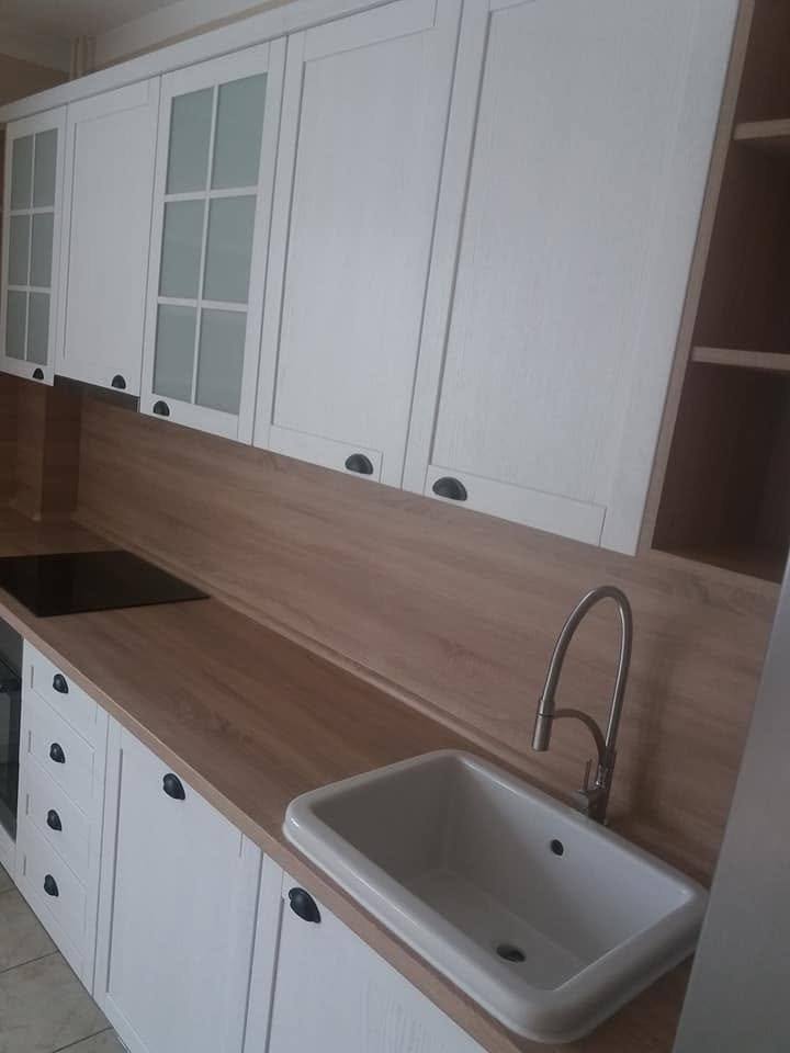 Weiße Rahmenkästen mit Vitrine über Keramikabwasch und Eichen-Rückwand