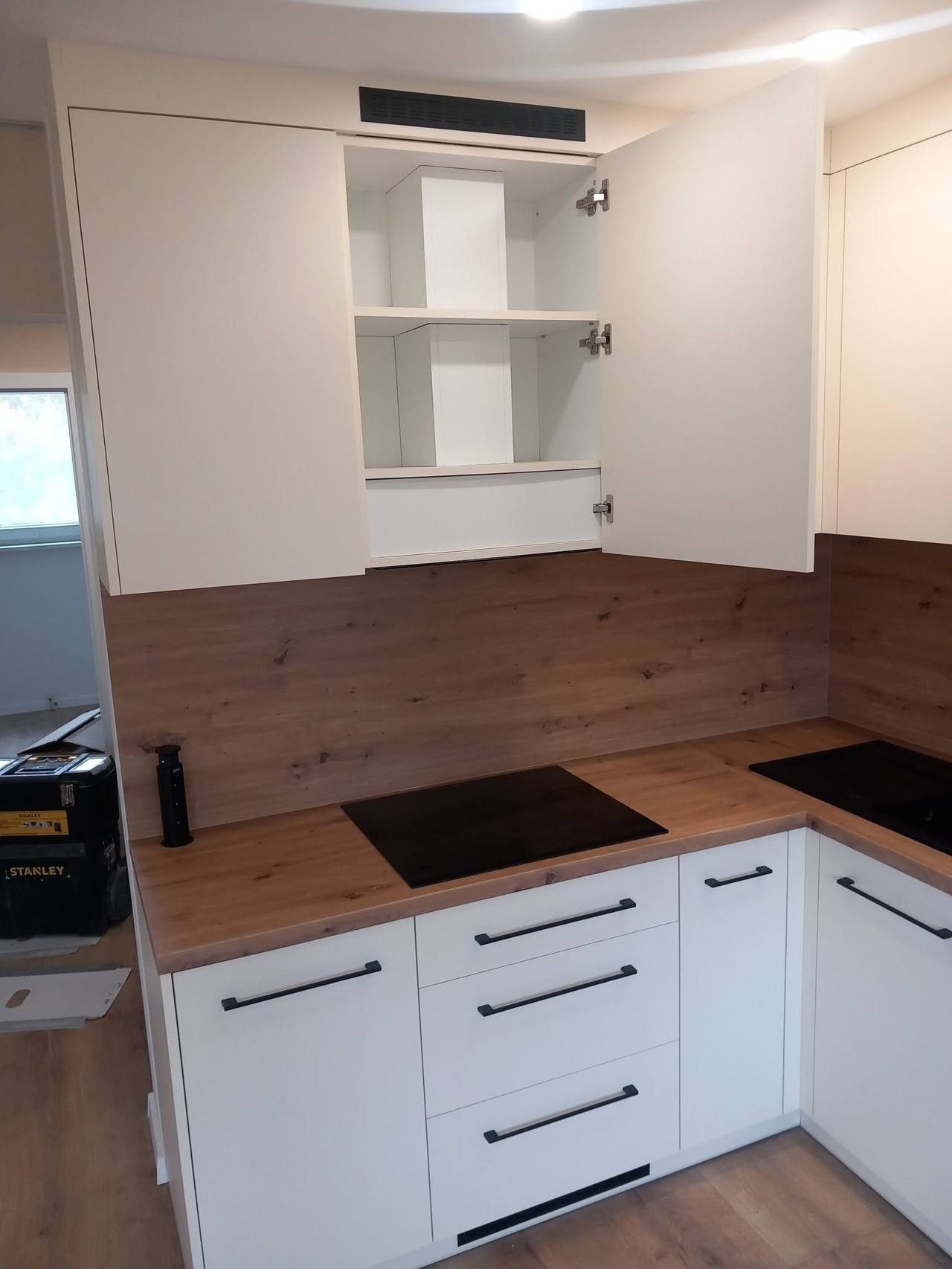 Weiße Küche mit geöffnetem Oberschrank und Eichendekor