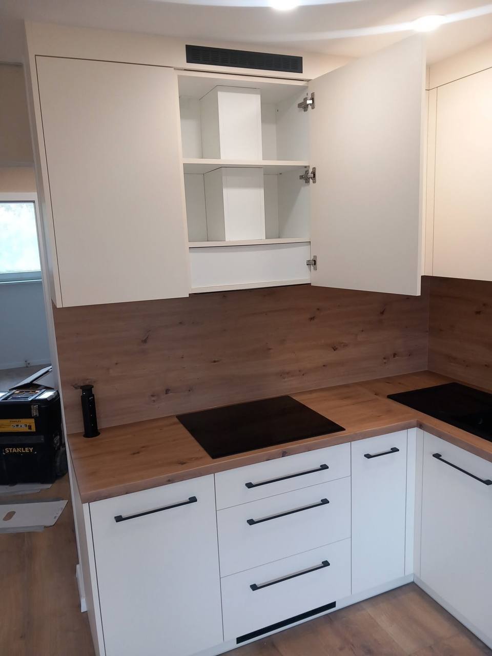 Weiße Küche mit geöffnetem Oberschrank und Eichendekor