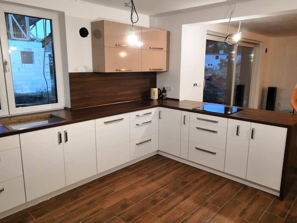 Weiße Eckküche mit Nussbaum-Rückwand und schwarzer Arbeitsplatte