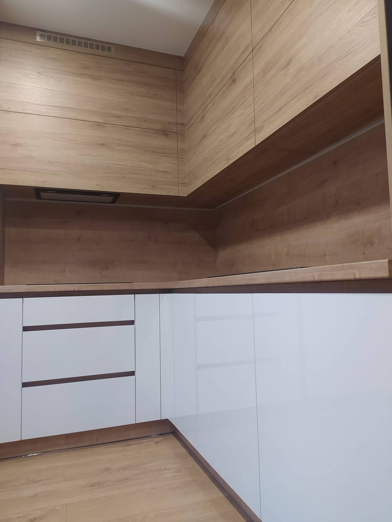 Weiße Küche mit schrägem Holz-Baldachin über der Ecke