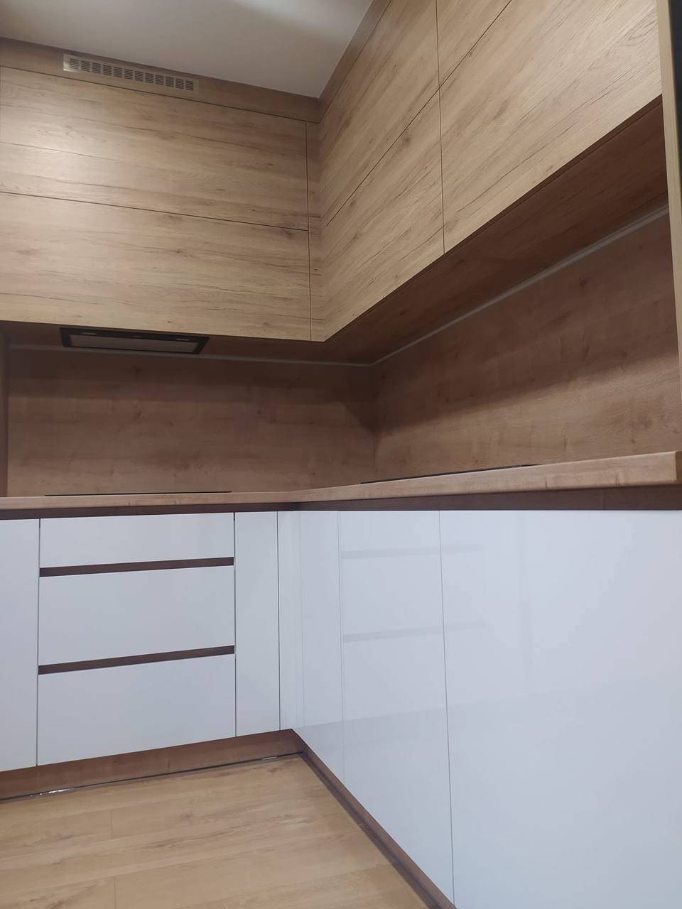 Weiße Küche mit schrägem Holz-Baldachin über der Ecke