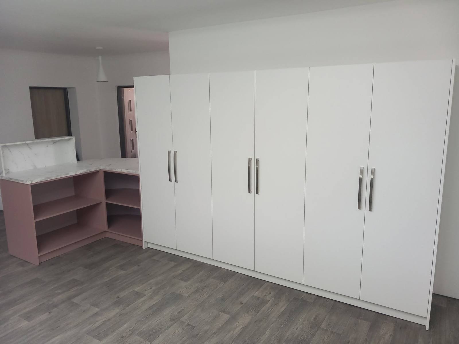 Weißer Kleiderkasten mit langen Griffen neben der Arbeitsecke