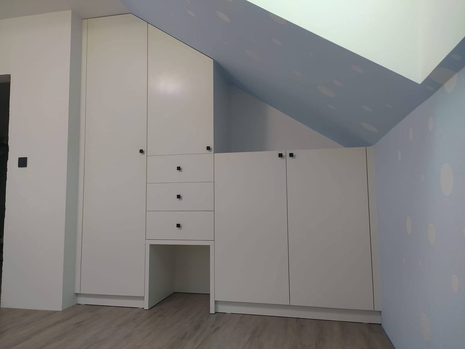 Weißer Kasten unter der Dachschräge mit drei Laden und niedrigen Kästen