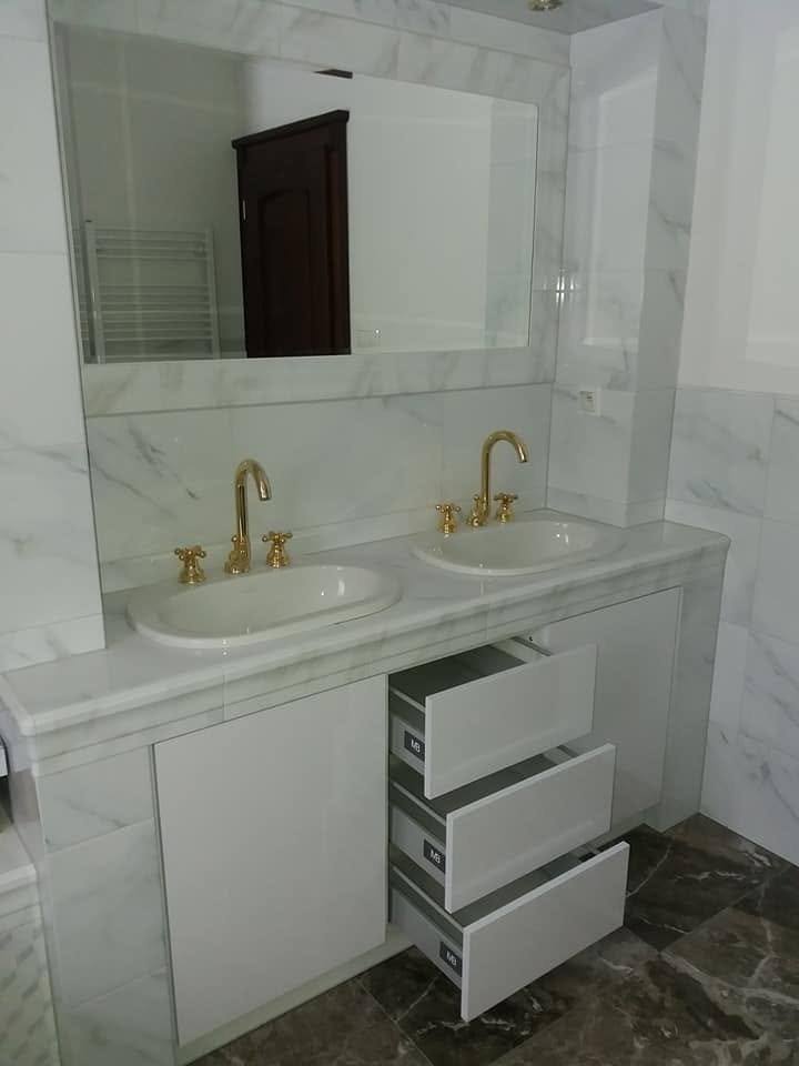 Weißer Badschrank mit Doppelbecken und goldenen Armaturen