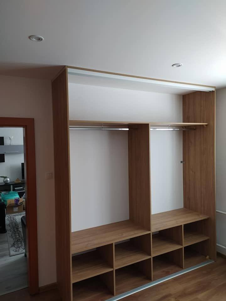 Offene weiße Kastenwand mit oberen Kästchen und Schuhregal.