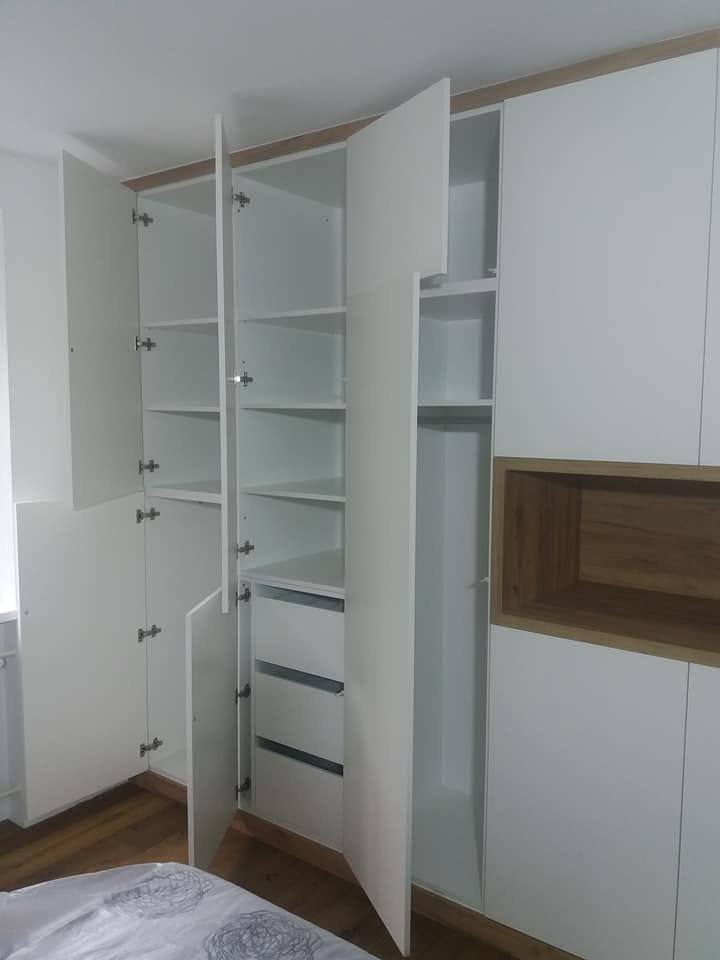 Geöffnete weiße Kastenwand im Schlafzimmer mit Laden und Fachböden.