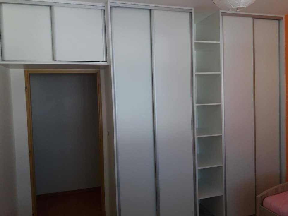 Weiße Kastenwand mit Oberkasten über der Tür und offenem Regal
