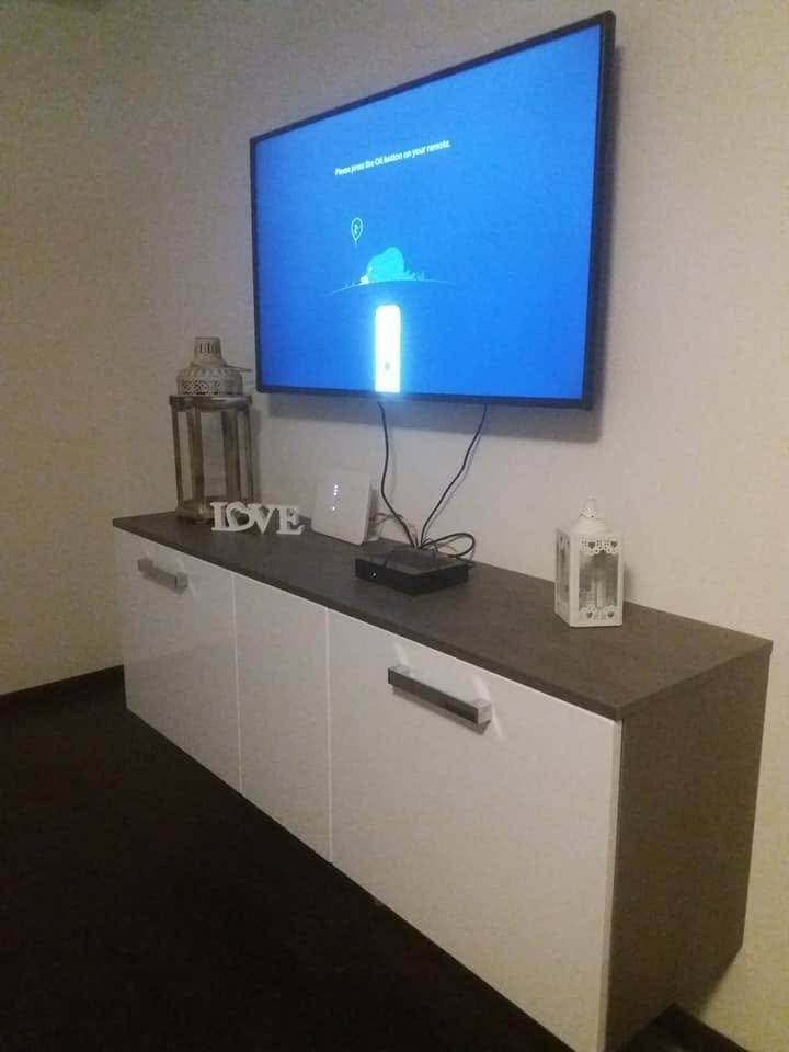 Weißes Lowboard mit dunkler Abdeckplatte unter dem Wandfernseher
