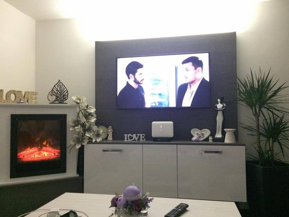 TV-Paneel mit indirektem Licht über dem weißen Lowboard beim Kamin