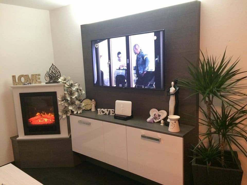 Weißes Lowboard und dunkles TV-Paneel neben dem Elektrokamin