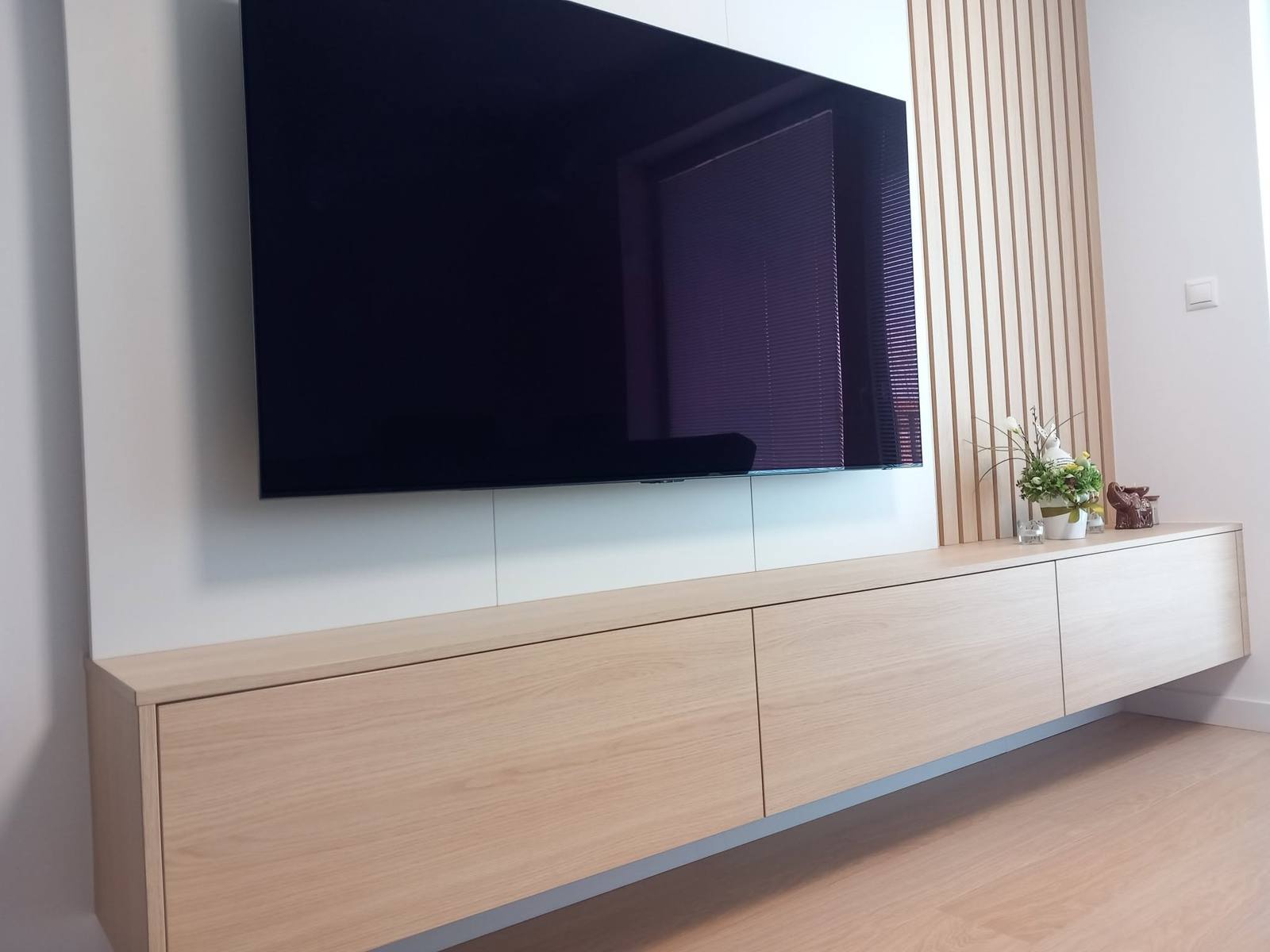 Langes Hängeelement in Eichenoptik unter dem großen Fernseher