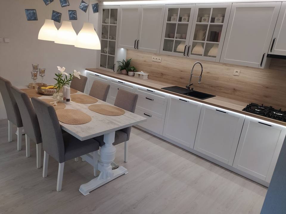 Weiße Landhauszeile mit Vitrinen neben langem Esstisch