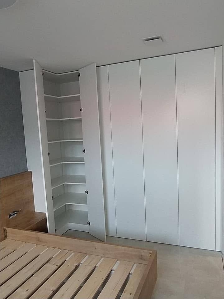 Weißer Einbaukasten bis zur Decke im Schlafzimmer mit offenem Seitenregal.