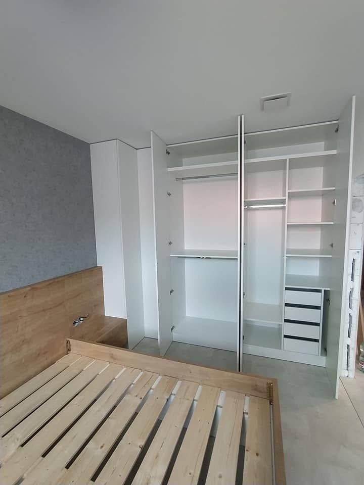 Geöffneter weißer Kasten mit Böden und Stange im Schlafzimmer.