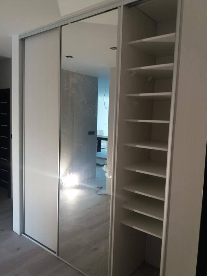 Weißer Einbaukasten mit Spiegeltür und offenen Fachböden.