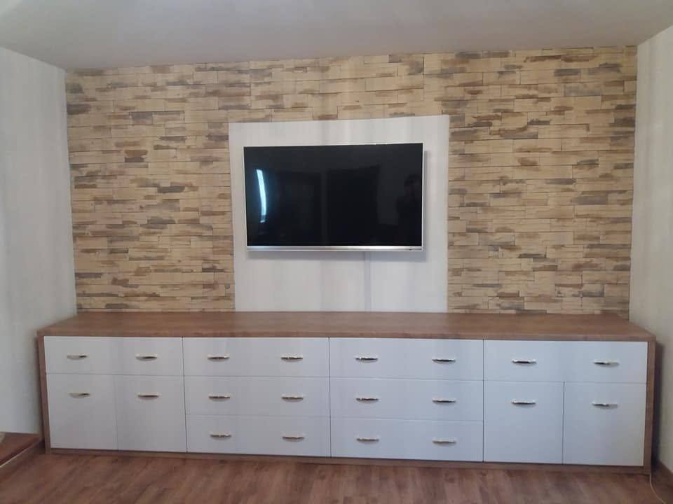 Lange weiße TV-Kommode unter dem Fernseher an der Steinwand