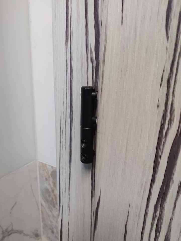 Schwarze Griffmuschel an der Schiebetür mit Holzmaserung