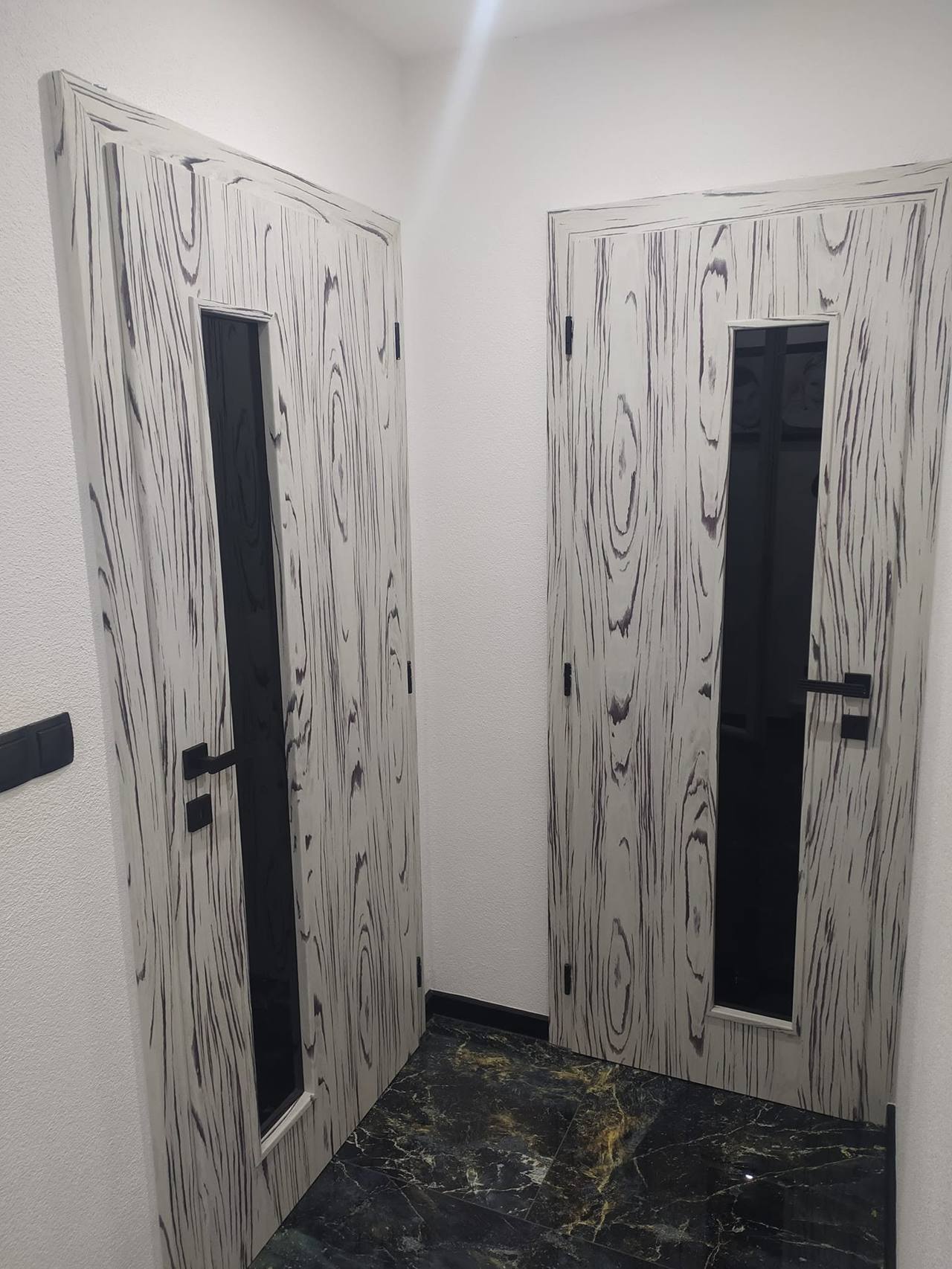 Zwei Türen mit schwarz-weißer Holzmaserung und schmalem Glas