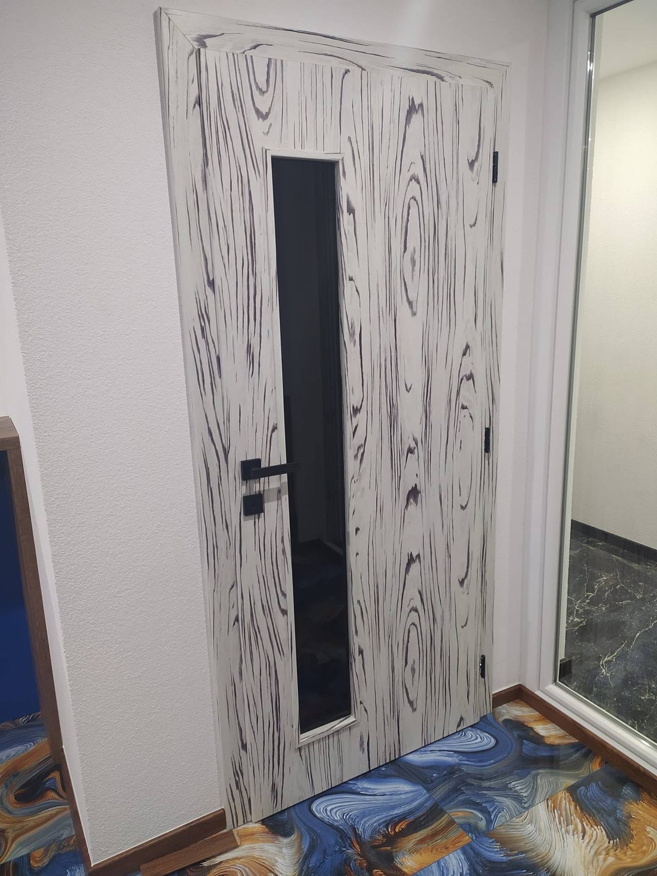 Weiße Tür mit Jahresring-Zeichnung und schwarzem Glasstreifen