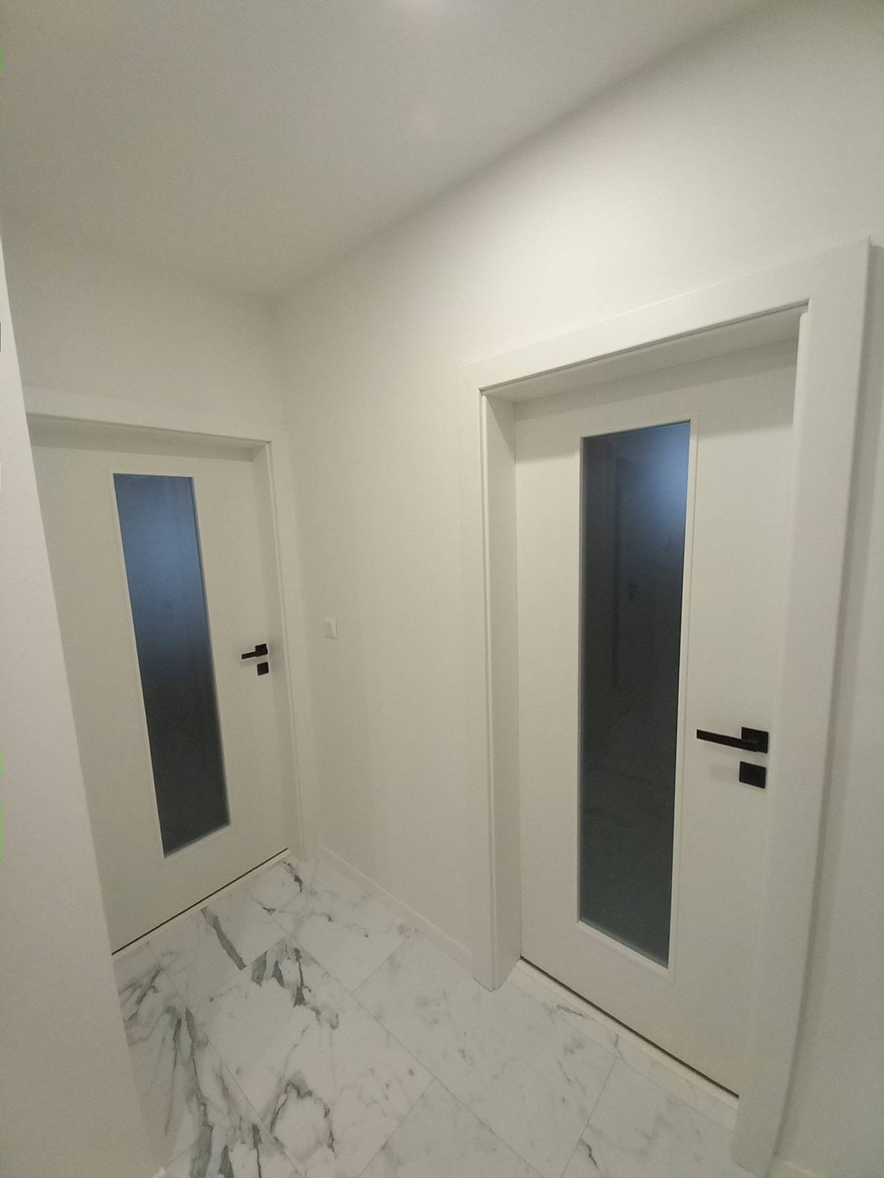 Weiße Tür mit dunklem Glas an der Wand aus anderem Blickwinkel