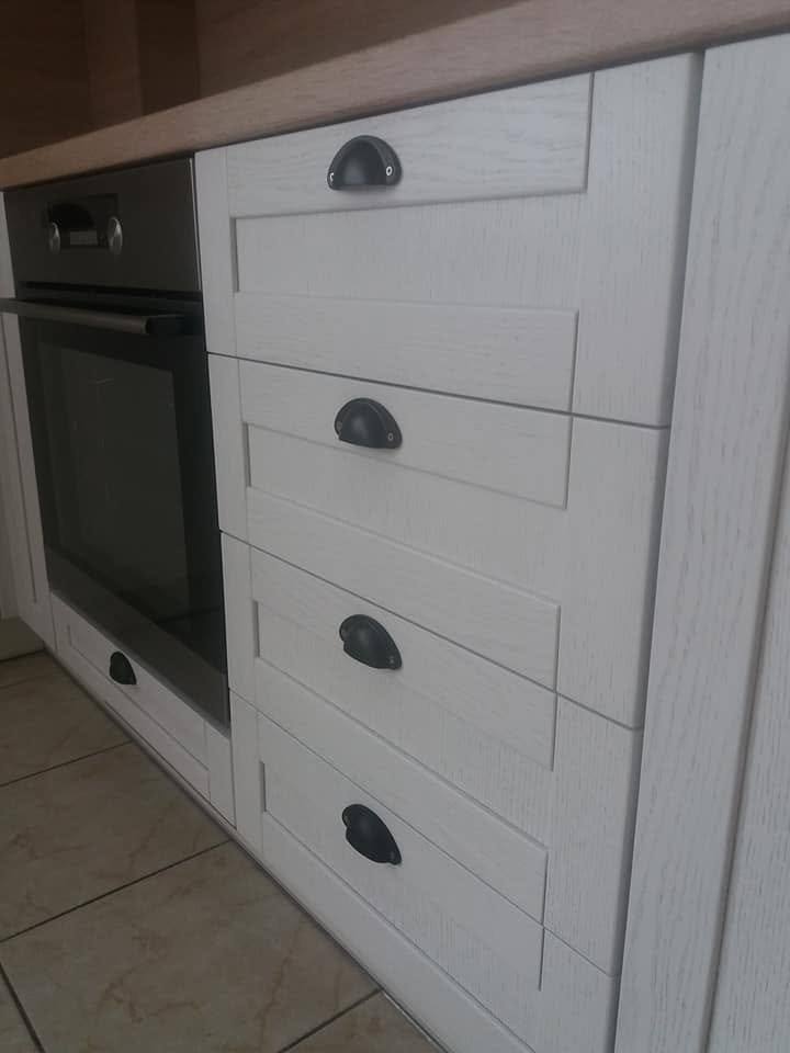 Weiße Rahmenladen mit schwarzen Griffen neben dem Einbau-Backrohr