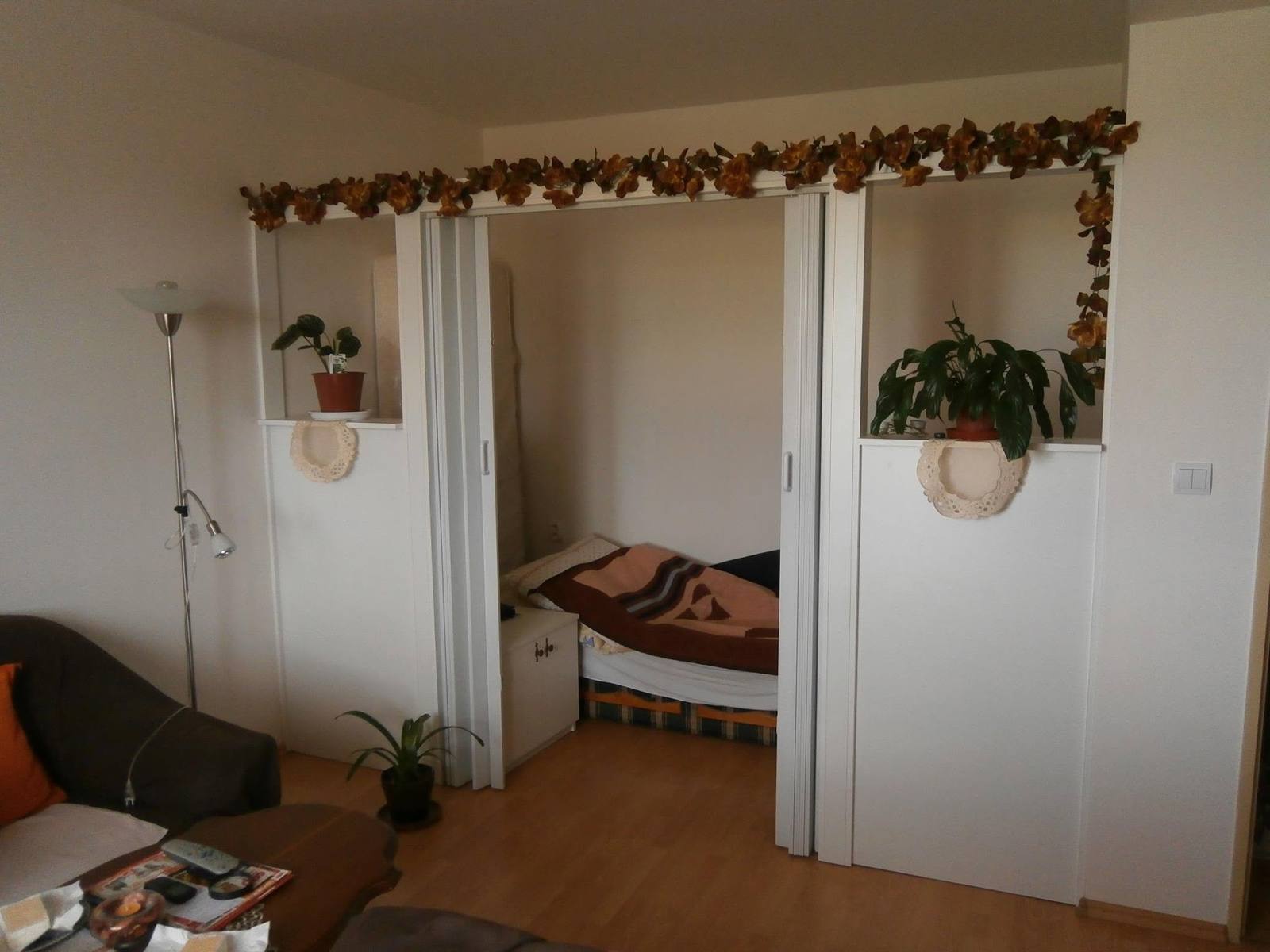 Weiße Falttür des Einbaukastens unter dem Regal mit Trockenblumen
