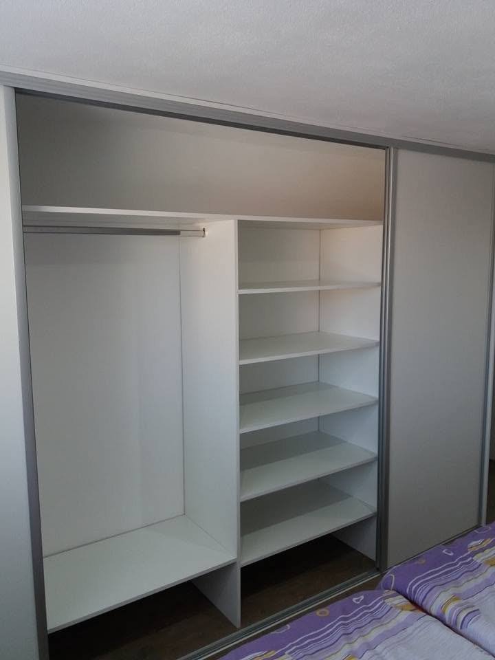 Geöffneter Kasten mit Kleiderstange und weißen Fachböden im Schlafzimmer