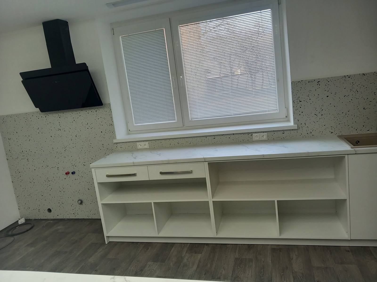 Weiße untere Küchenzeile mit offenen Borden am Fenster.