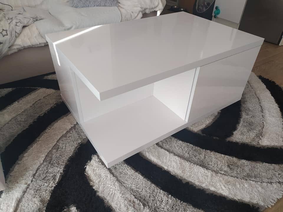 Weißer Hochglanz-Couchtisch mit offenem Fach auf dem Teppich