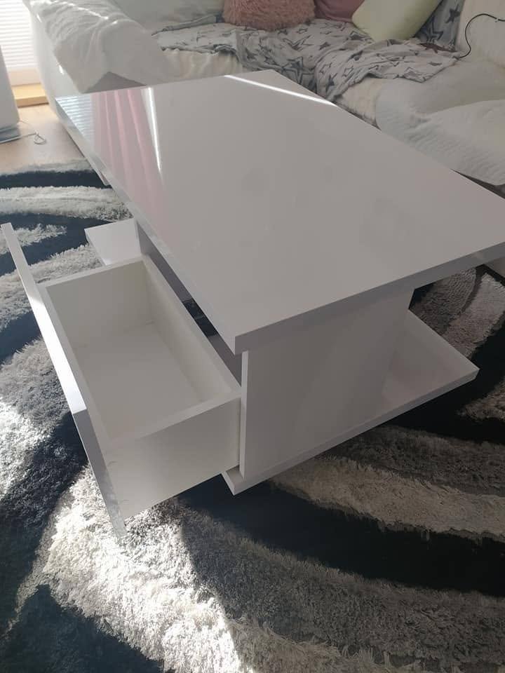 Weißer Couchtisch mit ausgezogener Lade auf dem Teppich