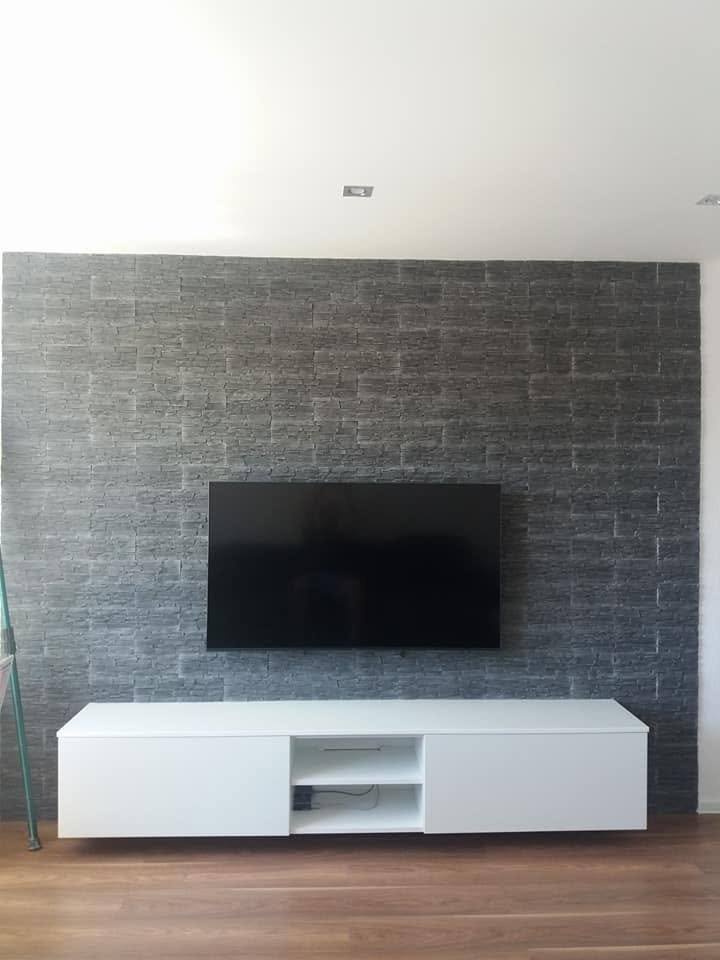 Weißes Lowboard unter dem Fernseher vor der Ziegelwand