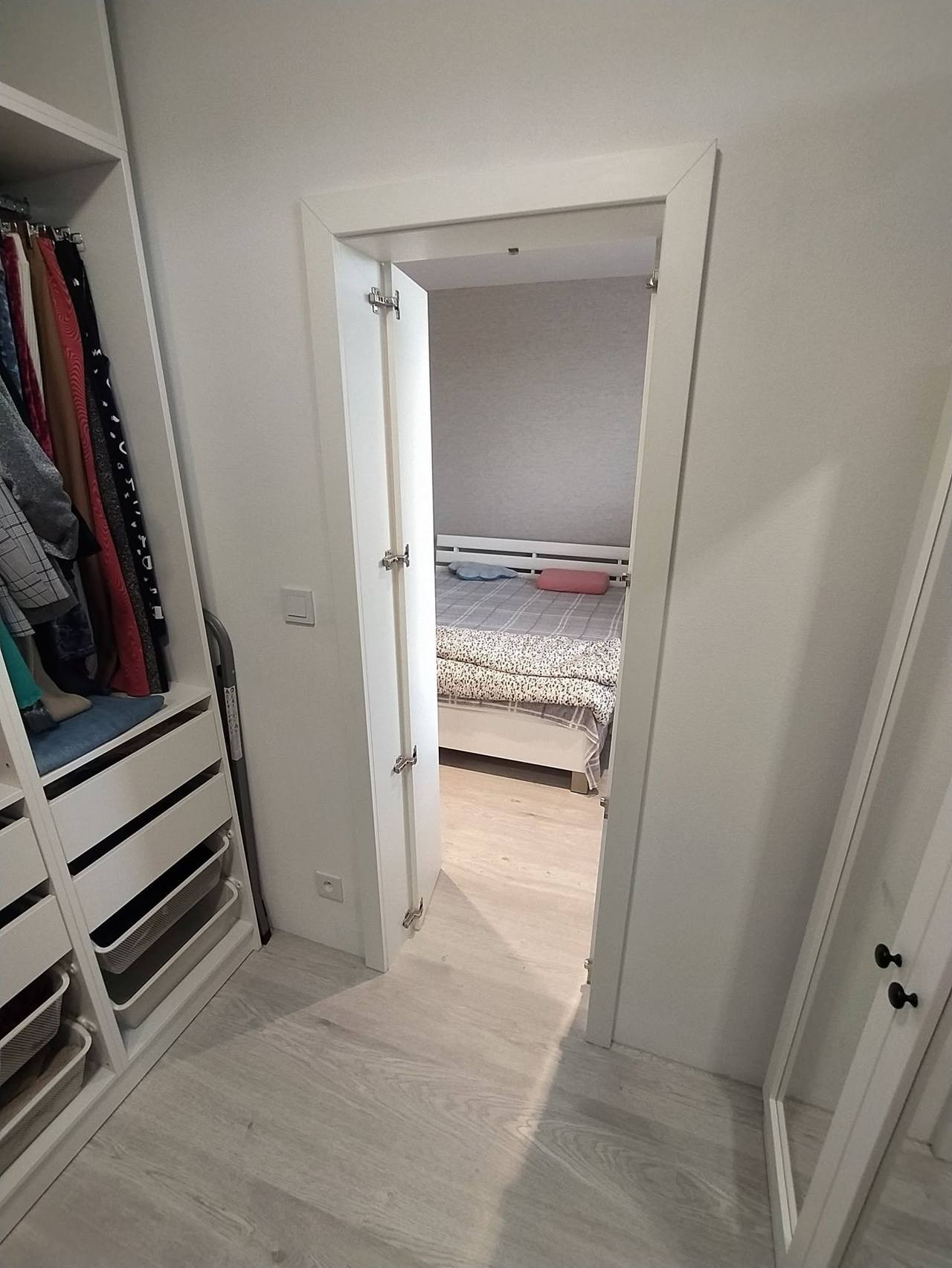 Pohľad zo šatníka s oblečením cez otvor do spálne