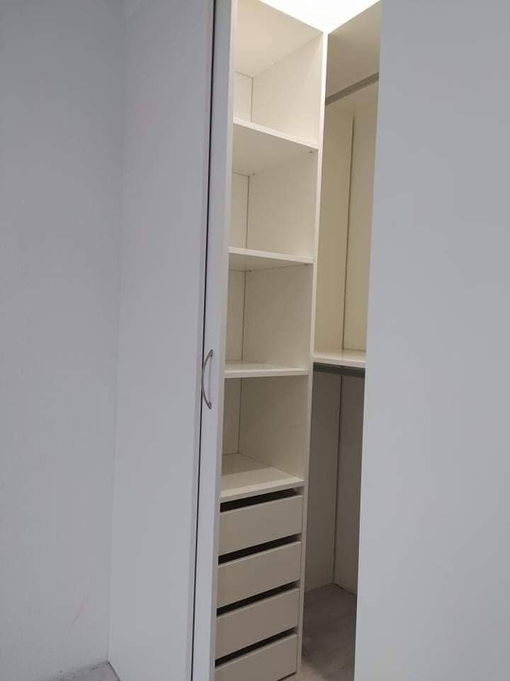 Biele police a zásuvky za vstupom do šatníka