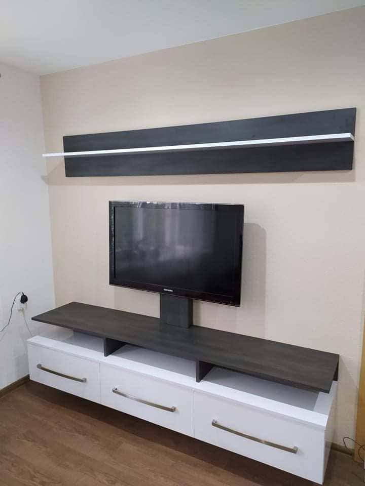 Weißes Lowboard mit Laden, Fernseher auf Säule und Wandbord darüber