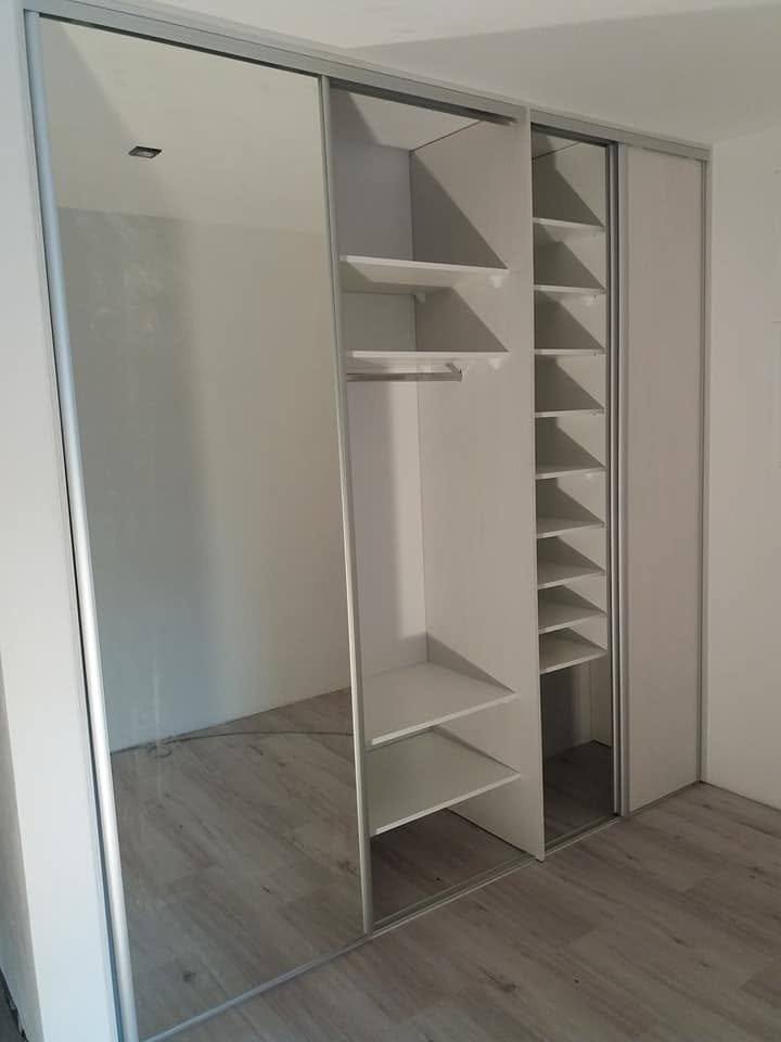 Weißer Innenausbau des Schiebetürkastens mit Spiegeltür und Kleiderstange.