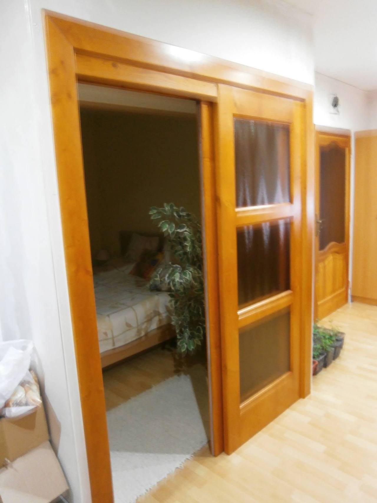 Geöffnete Kiefernholztür mit Blick ins Schlafzimmer mit Bett