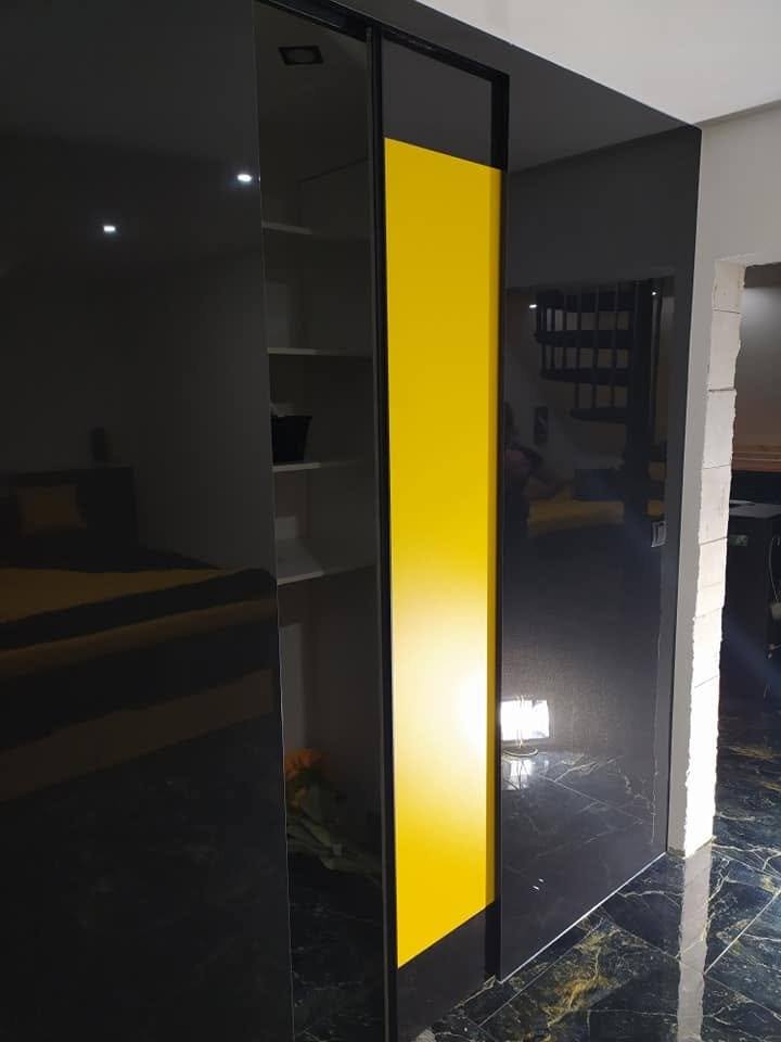 Detail žltého krídla s čiernym rámom v lesklej čiernej stene