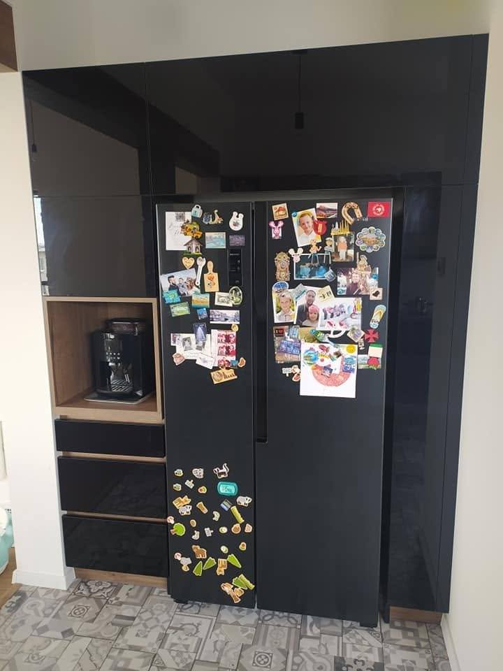 Schwarzer Kühlschrank mit Magneten zwischen raumhohen Hochkästen