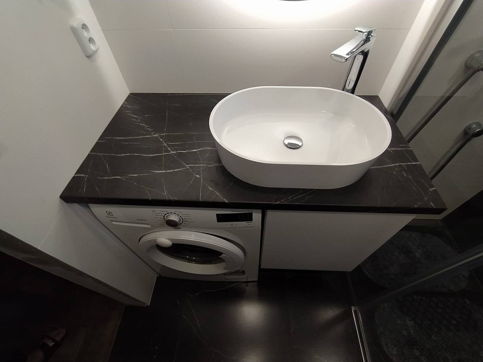 Schwarze Marmorplatte mit Becken über der Waschmaschine