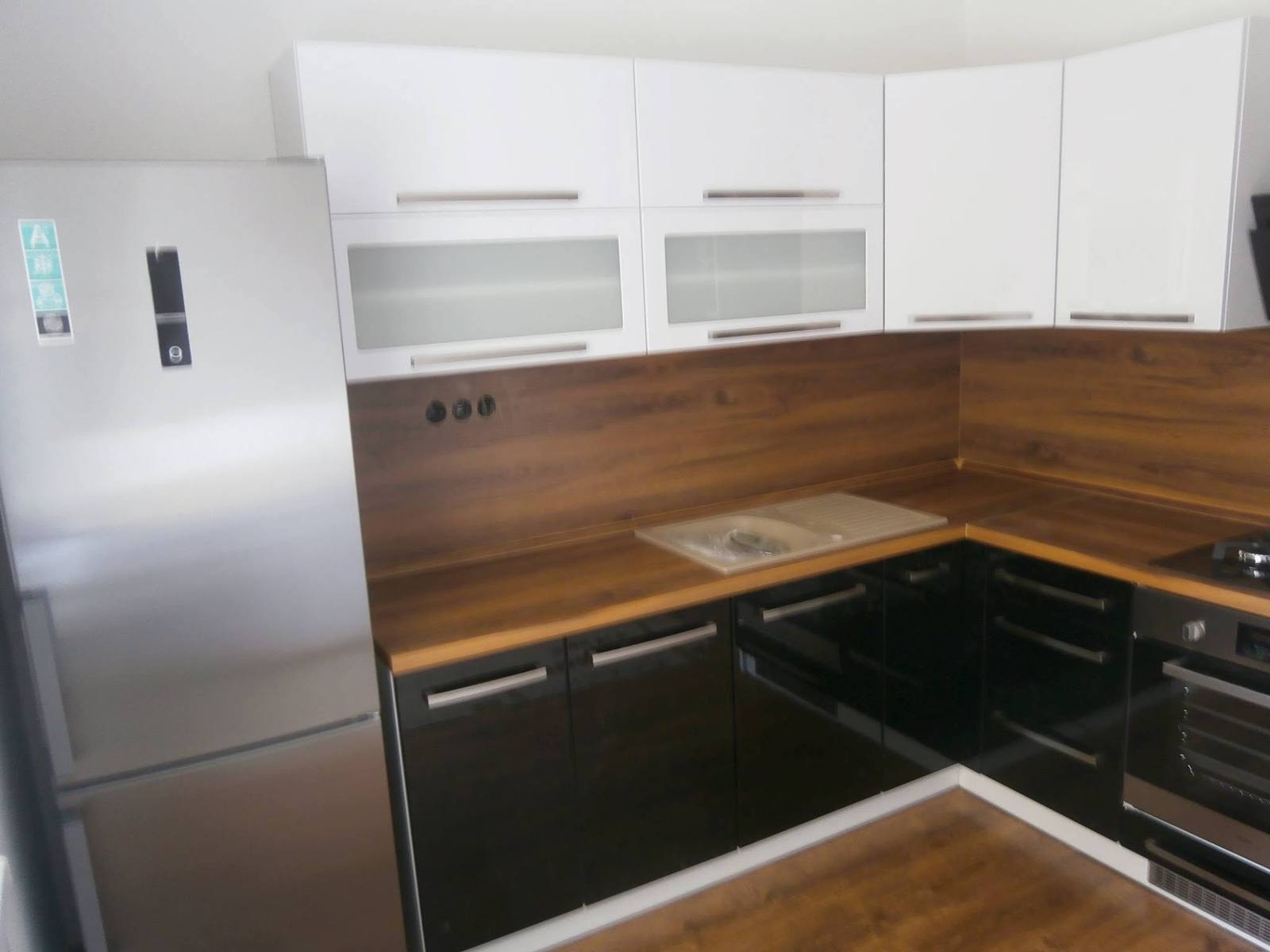 Schwarz-weiße Eckzeile mit Nussbaumplatte und Kühlschrank