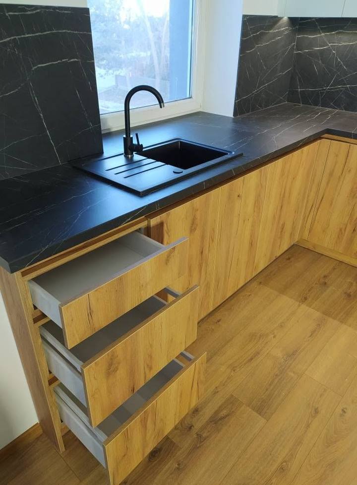 Detail der dunklen Arbeitsplatte mit schwarzer Spüle und ausgezogener Lade