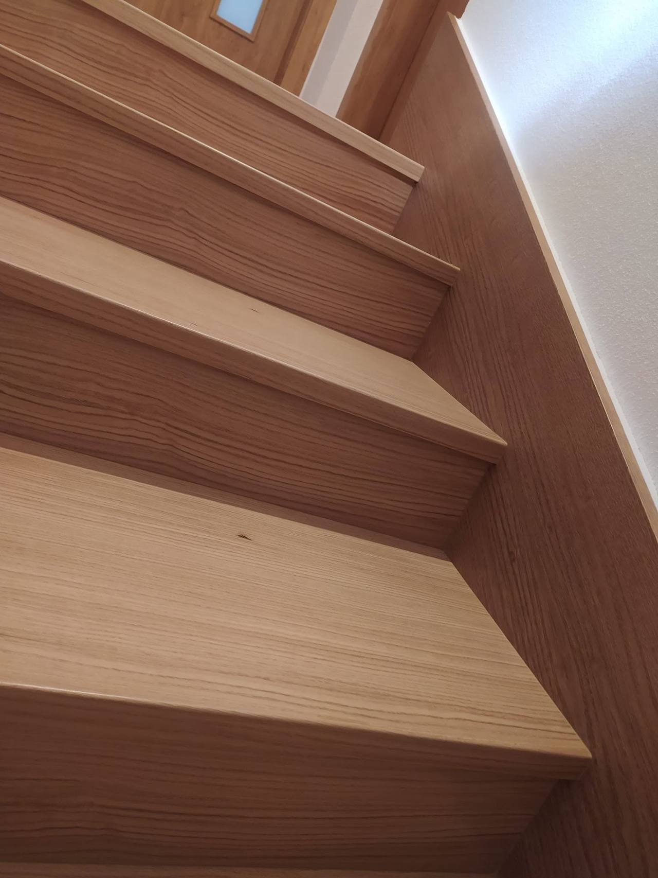Helle Eichentrittstufen und Setzstufen an der weißen Wand