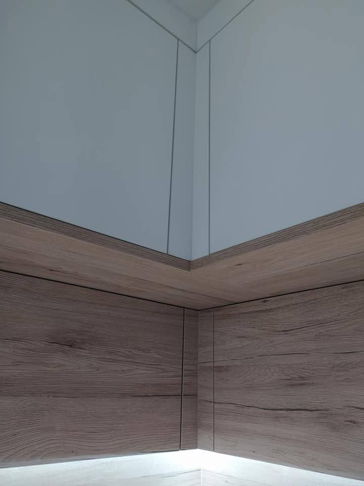 Raumecke mit Wandspiegel in Eichendekor und LED-Streifen.