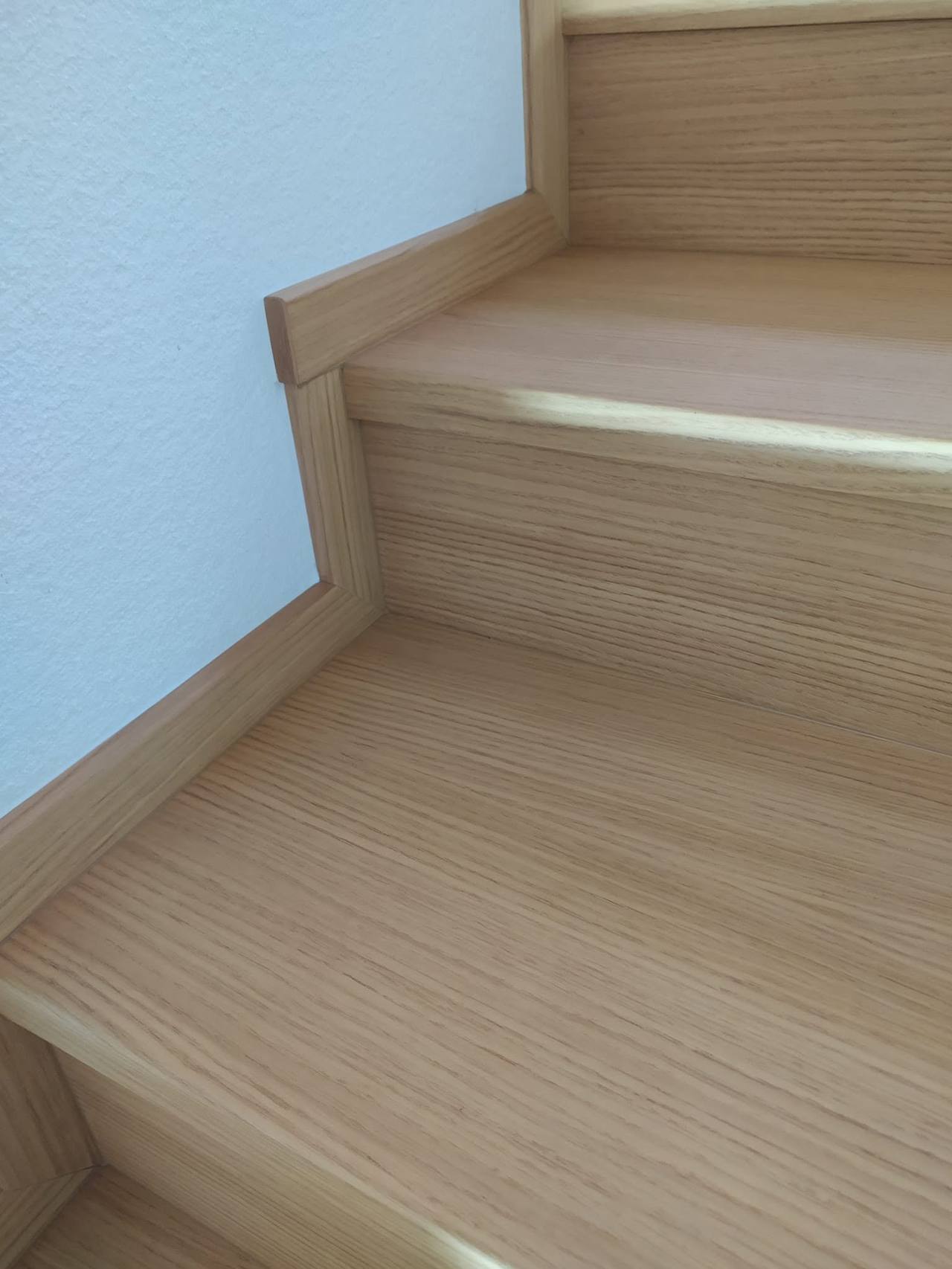 Helle Eichenstufen der Stiege mit Leiste entlang der Wand
