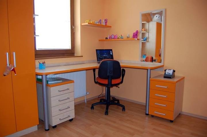 Schreibtisch mit Rollcontainer und orangefarbenem Schrank im Kinderzimmer